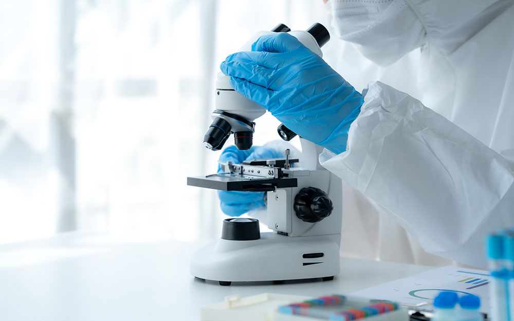 Doctor hand taking a blood sample tube from a rack with machines of analysis