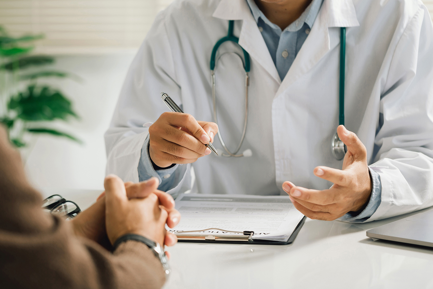 physician in a white medical uniform talks to discuss results to a male patient